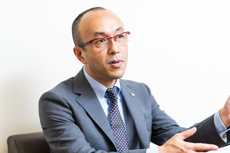 Masahiro Kisono of Ricoh’s Platform Business Group (pictured). The 9 dan Toshiyuki Moriuchi, then a director of the Japan Shogi Association and a backgammon aficionado, learned about a backgammon recording system that Mr. Kisono developed as pet project. Mr. Moriuchi asked Mr. Kisono if it might be possible to create a similar system for shogi, triggering the development of Ricoh’s setup.